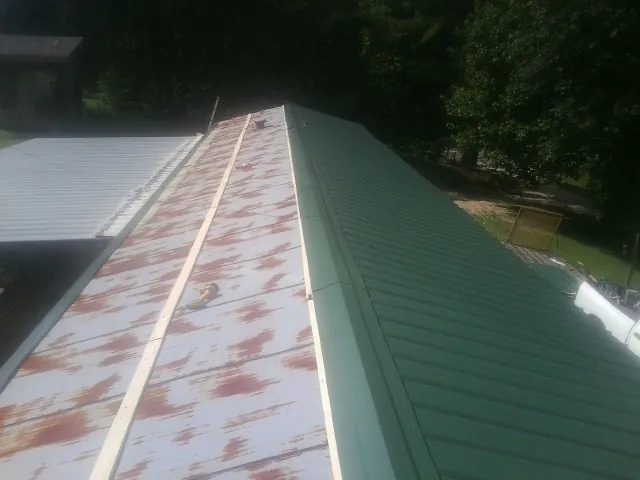 Old rusted panels beside newly installed green metal roofing — Wind Damage Roof Repair by Roofing Brothers in Zeeland