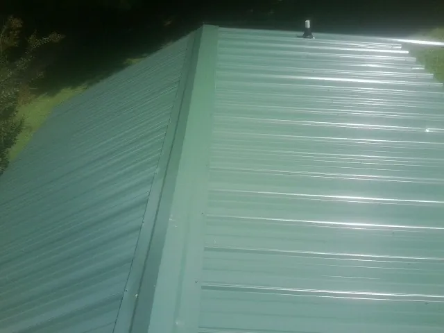 New green metal panels meeting at the ridge of a roof — Flat Roof Repair work by our crew in Zeeland