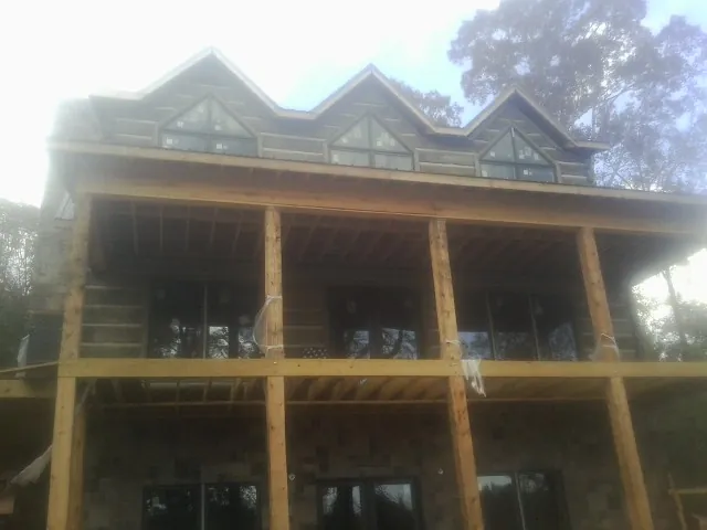 Dormers and porch framing on a large log home under construction — Roof Coating work by our crew in Zeeland