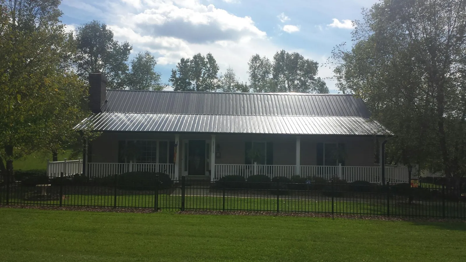 Gray metal roof on a brick ranch with a full width front porch — Gutter Guard Installation work by our crew in Zeeland