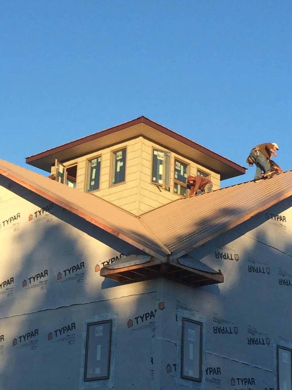 Roofers working around a rooftop cupola on a new metal roof at sunset — Roof Waterproofing in Zeeland by Roofing Brothers